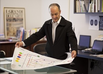 man in jacket holding a large map on the desk