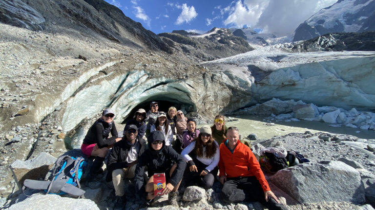 group of students and faculty posing with a glacier